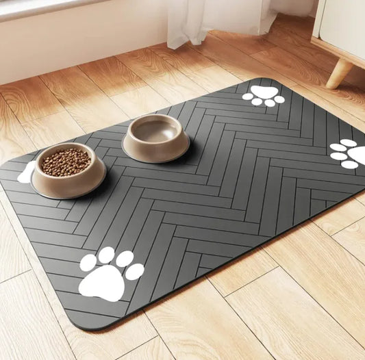 Gray pet mat with paw prints on a wooden floor with two bowls of food.